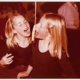 Two girls trying to eat the treacle scone on Halloween.