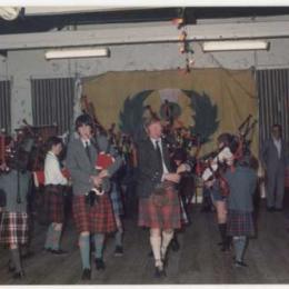 Andy Robertson stands to the right watching the pipers.