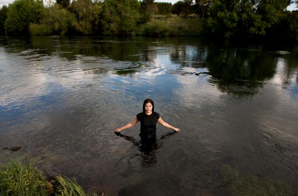 Young wahine standing in the water of the river in Te Teko arms stretched out