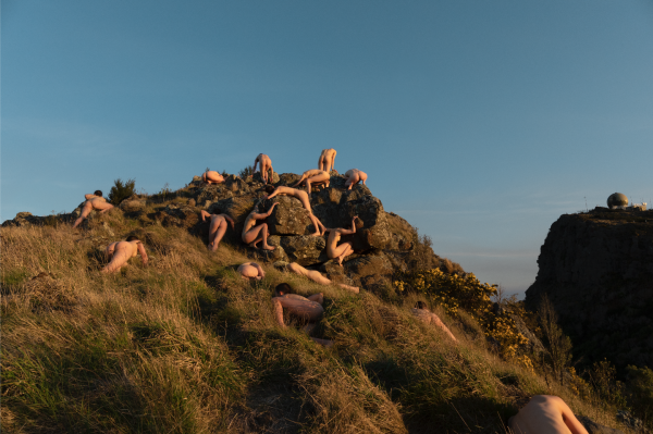 Human figures peppered throughout the landscape, grassy hill and blue sky
