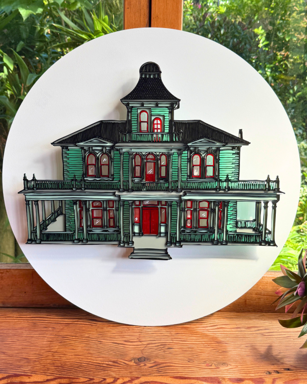 A replication of Antrim House made of acrylic is secured onto a white circular backing 