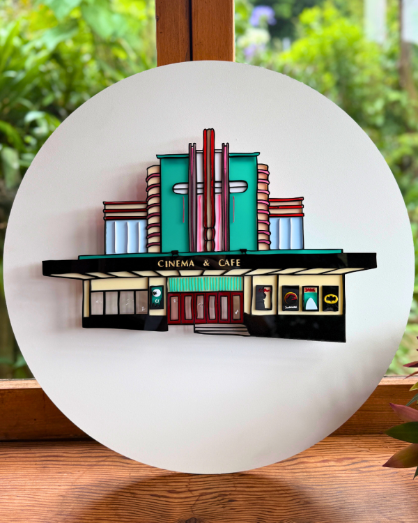 A replication of The Penthouse made of acrylic is secured onto a white circular backing 