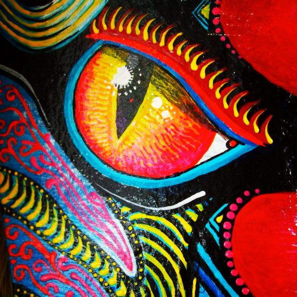 Detail of 'Devi" a mask by James Harcourt. A phoenix palm leaf painted with an animalistic facebright paint 