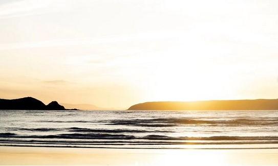 Photograph by Kobi Maibach. Landscape image of waves and headlands in delicate dawn light.