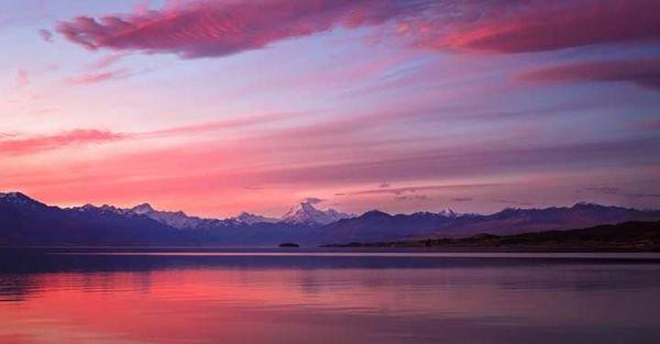 Landscape of harbour and hills at sunset, washed with lavendar and blush pink light. Photograph by Amelie Bently.