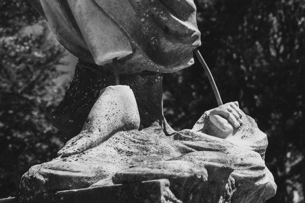 Black and white photo, tighly cropped of a graveyard staues with broken feet. By Bree Wogan.